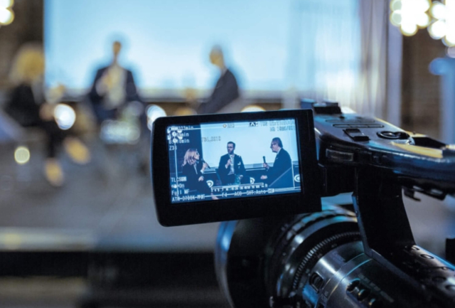 People being interviewed through the lens of a camera