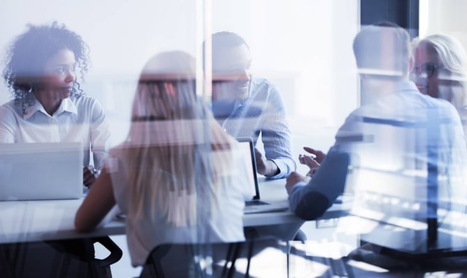 A group of office workers sit around a table generating ideas